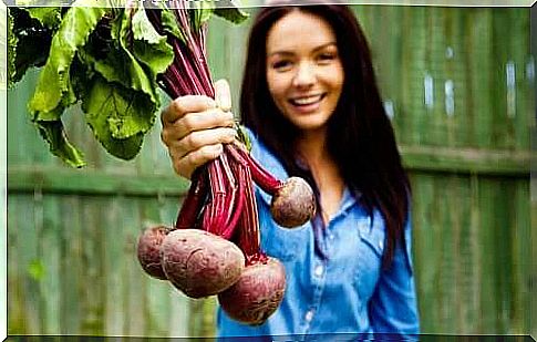 A woman holding beets in her hand