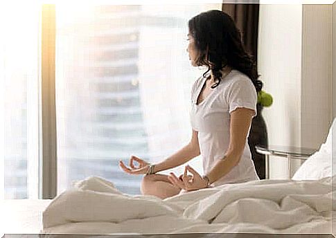 A woman who has adopted a healthy habit and is meditating in her bed