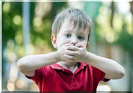 A child covering his mouth. 